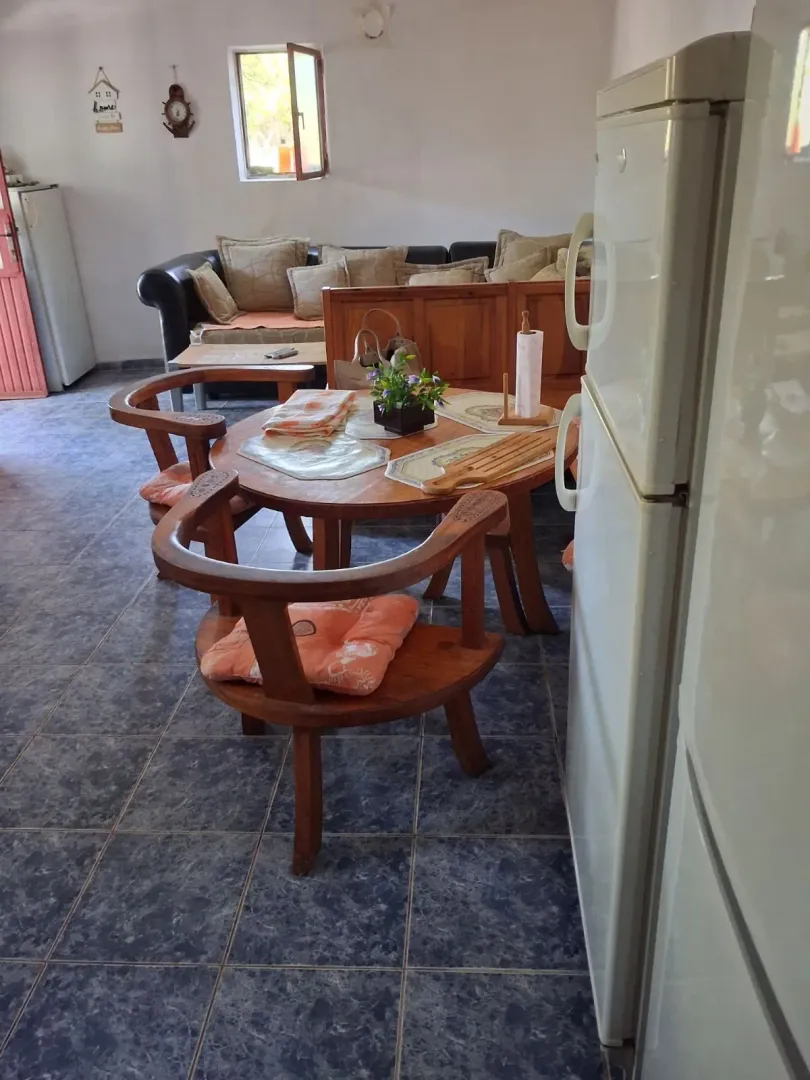 Living room with a dining table and kitchen elements in the background.