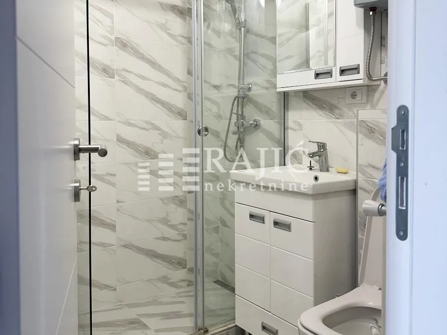 Modernly equipped bathroom with a shower cabin and sink.