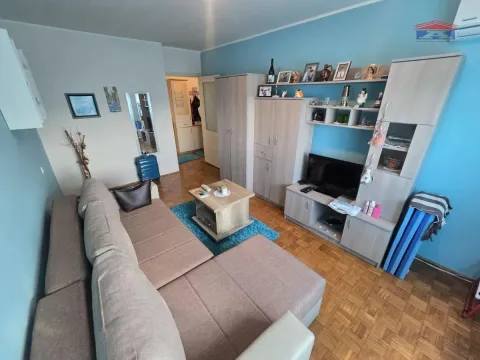 Dnevna soba sa ugaonom garniturom, TV-om i nameštajem svetle boje drveta. - image 7