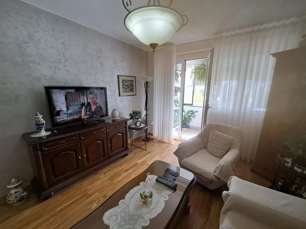 Dnevna soba sa garniturom, televizorom i izlazom na terasu.