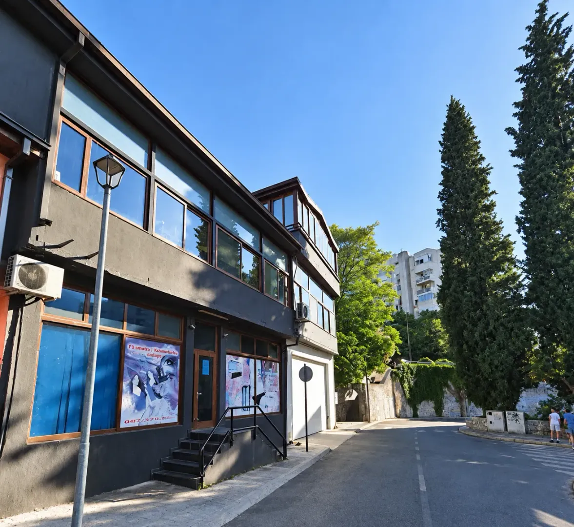 View of the exterior of a commercial building with a dark facade and large windows on the street.