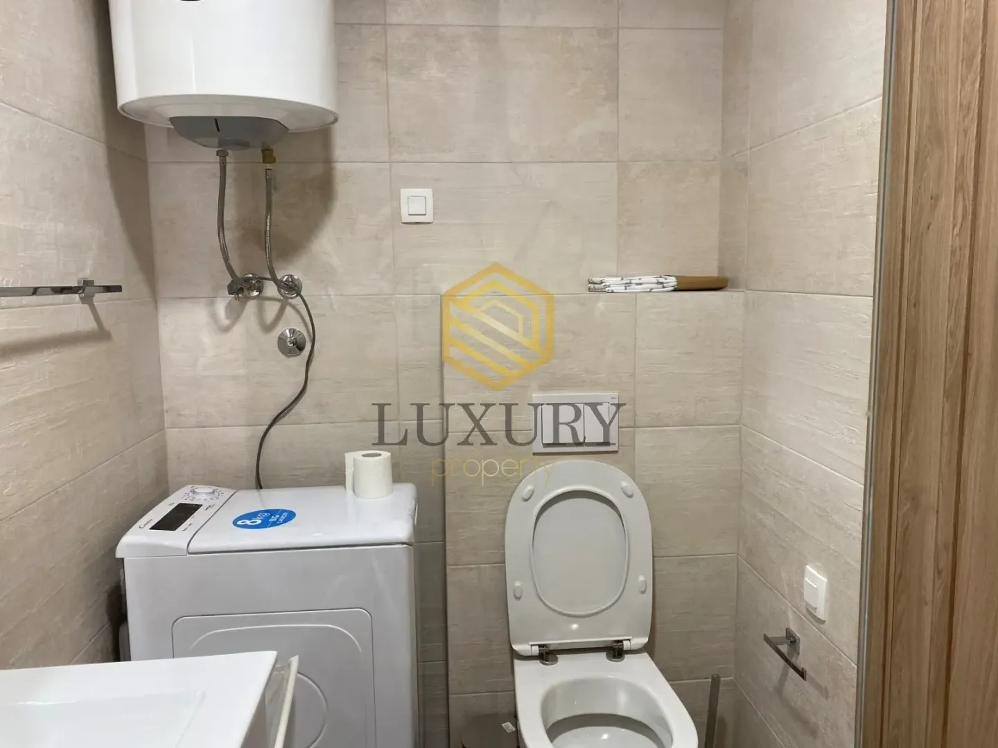 Small bathroom with a toilet, washing machine and water heater.