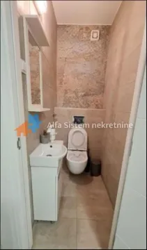 Smaller bathroom tiled with ceramic tiles featuring a sink and a toilet. - image 9