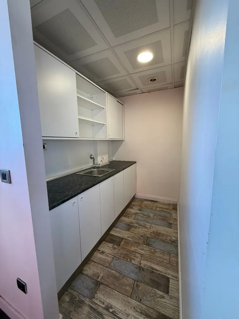 Small kitchenette with white cabinetry and a sink.