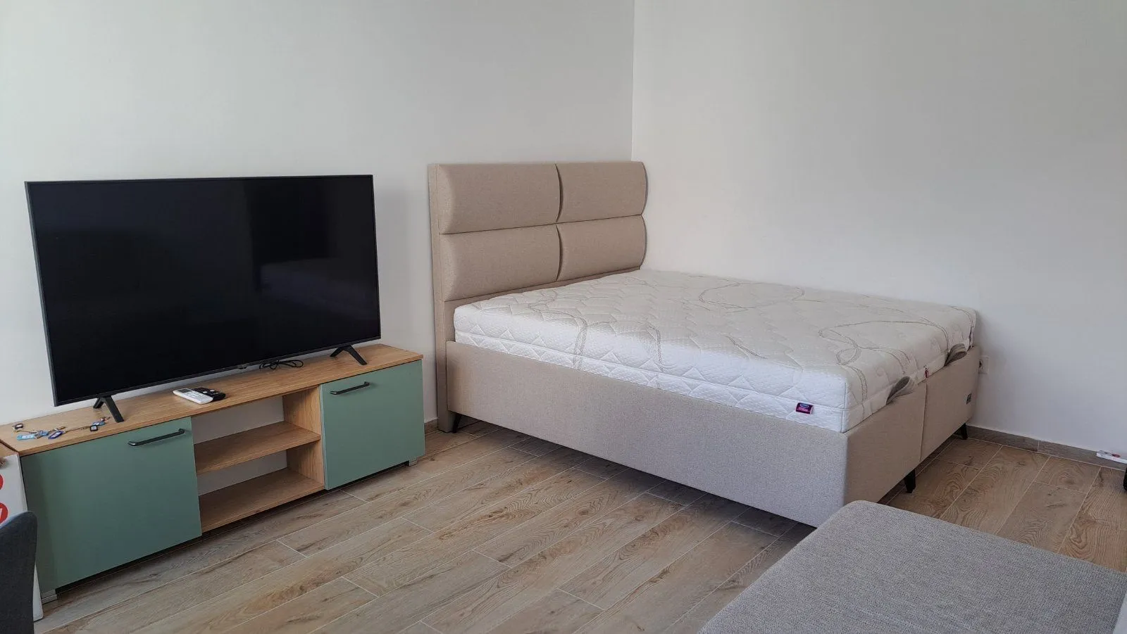 Spavaća soba sa bračnim krevetom, televizorom i komodom.