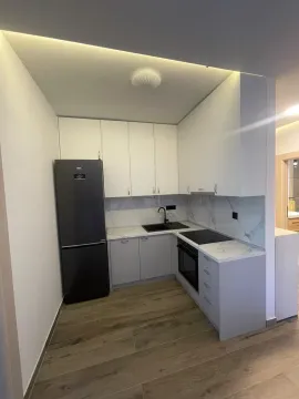 Moderna bijela kuhinja sa ugradnim uređajima i crnim frižiderom. - image 3