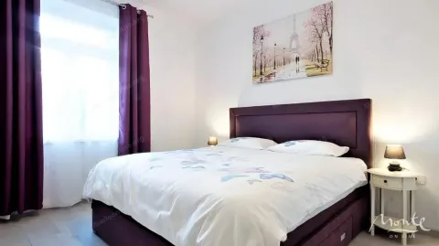 Spavaća soba sa bračnim krevetom i ljubičastim zavesama. - image 7
