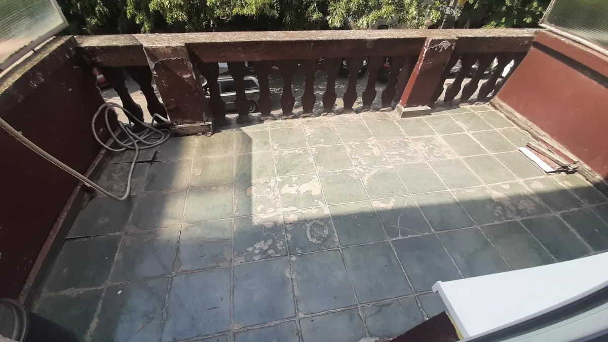 Manji popločani balkon sa starom betonskom ogradom.