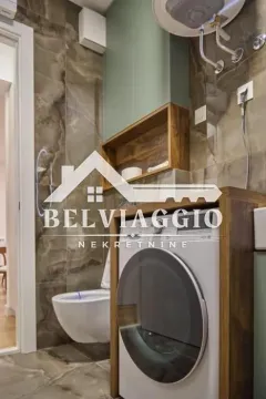 Bathroom with washing machine, toilet bowl, and modern tiling. - image 17