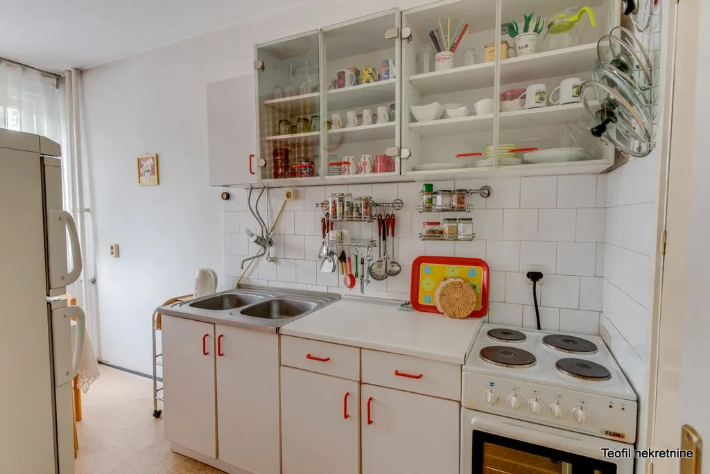 Compact kitchen with white cabinets, a sink, and an electric stove.