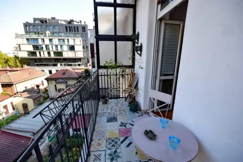 Manji namešteni balkon sa stolom i pogledom na okolne zgrade. - image 3