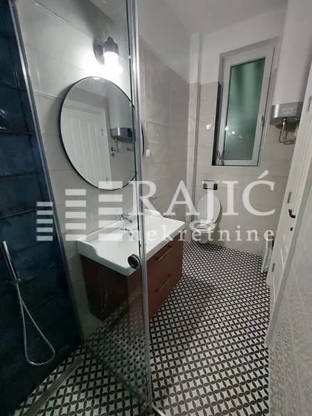 Modern bathroom with a shower cabin, vanity, and toilet.