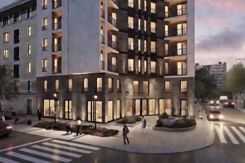 Exterior of a modern residential building with dusk lighting and a street in the foreground.