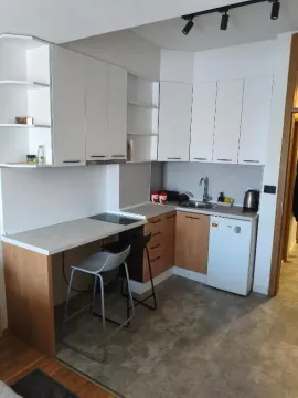 Small modern kitchen with white cabinets and a breakfast bar with chairs. - image 15
