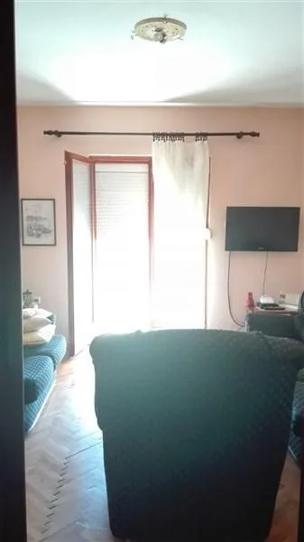 Dnevna soba sa garniturom za sjedenje i balkonskim vratima.
