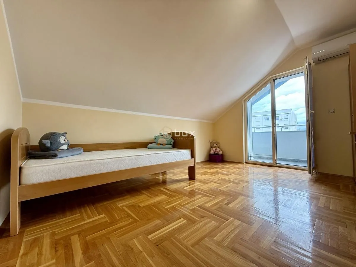 Attic bedroom with a wooden bed and parquet flooring.