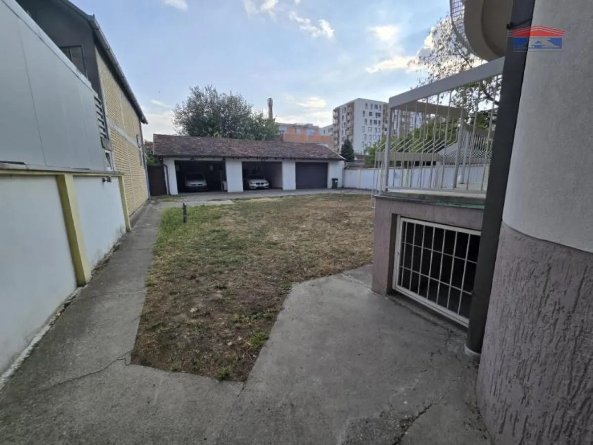 Yard with an outbuilding and garages in the background.