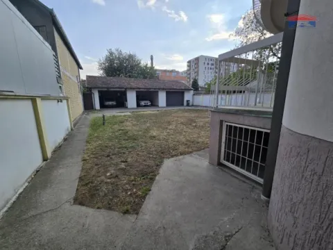 Yard with an outbuilding and garages in the background. - image 18