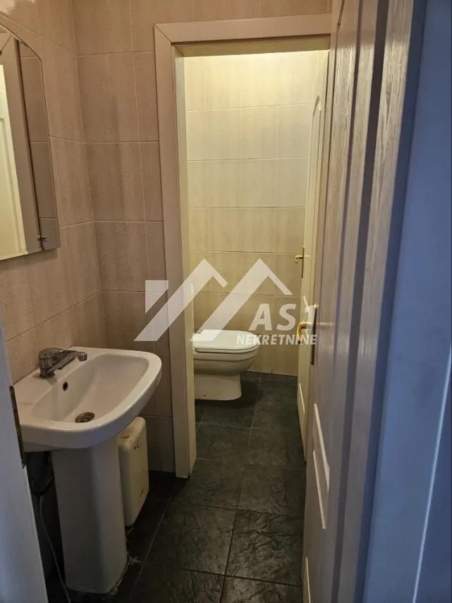 View of the bathroom with a washbasin in the foreground and a toilet in the back.