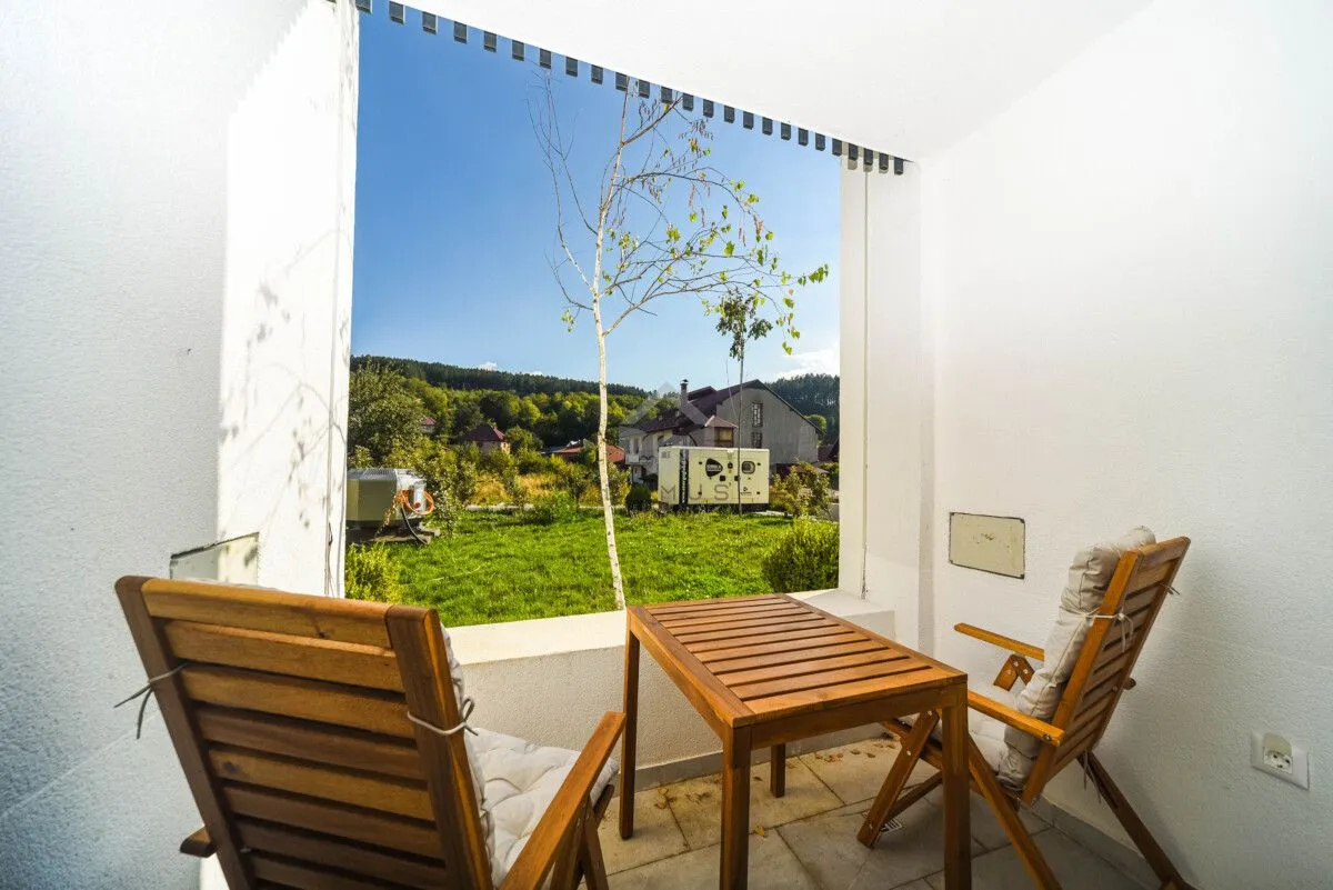 Covered terrace with a wooden table and chairs and a view of the yard and nature.
