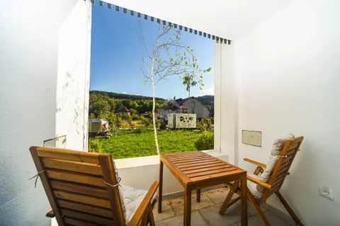 Covered terrace with a wooden table and chairs and a view of the yard and nature. - image 7
