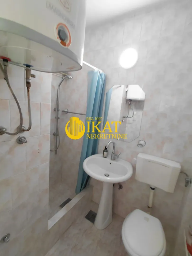 Smaller bathroom with a shower cabin, washbasin, and toilet.