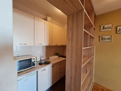 A small kitchen with light cabinets and a wooden room divider shelf. - image 8