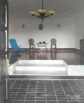 Spacious living room with wooden flooring, marble steps, and a chandelier. - image 12
