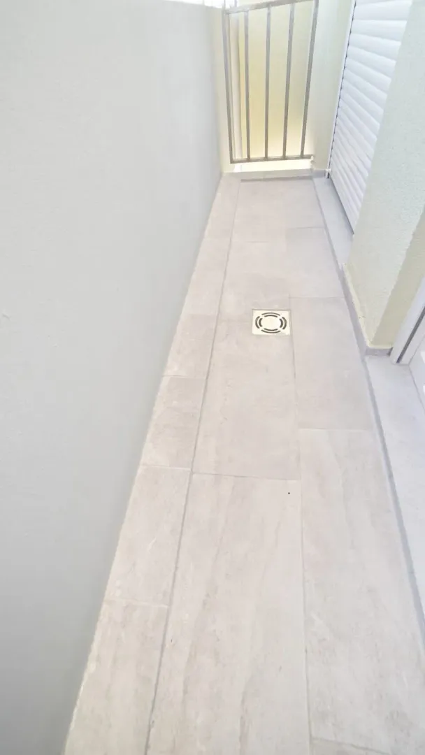 Narrow balcony with tiled flooring and metal railing.