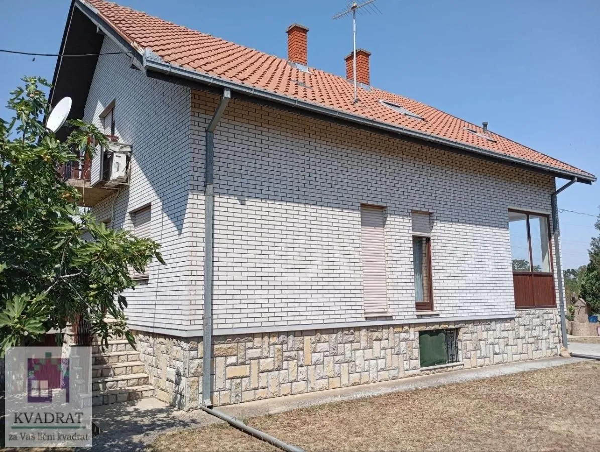 Pogled na spoljašnjost kuće sa fasadom od cigle i krovom od crepa.