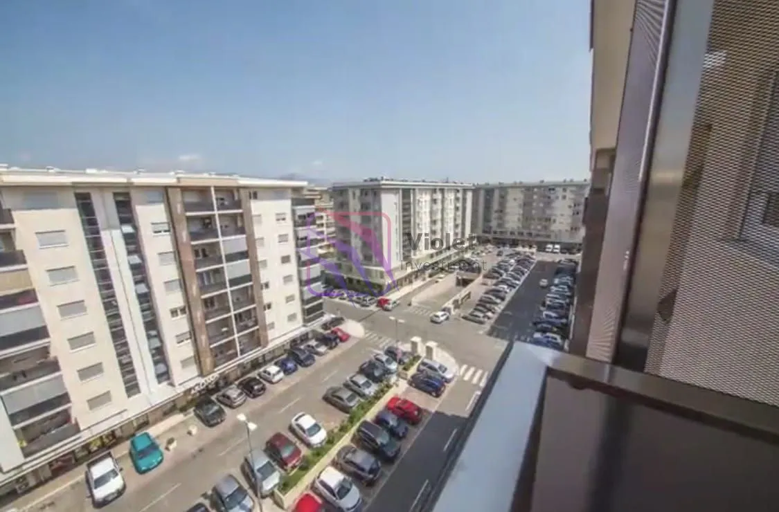 View from the balcony overlooking surrounding residential buildings and parking lot.