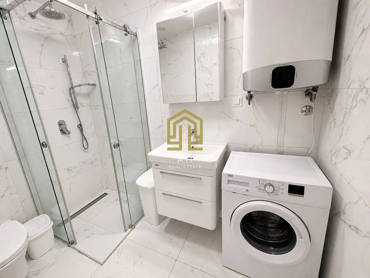 Modernly equipped bathroom with a walk-in shower and washing machine.