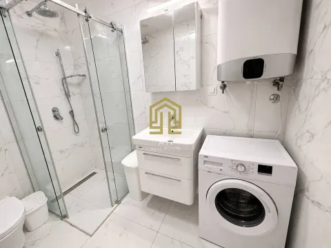 Modernly equipped bathroom with a walk-in shower and washing machine. - image 7