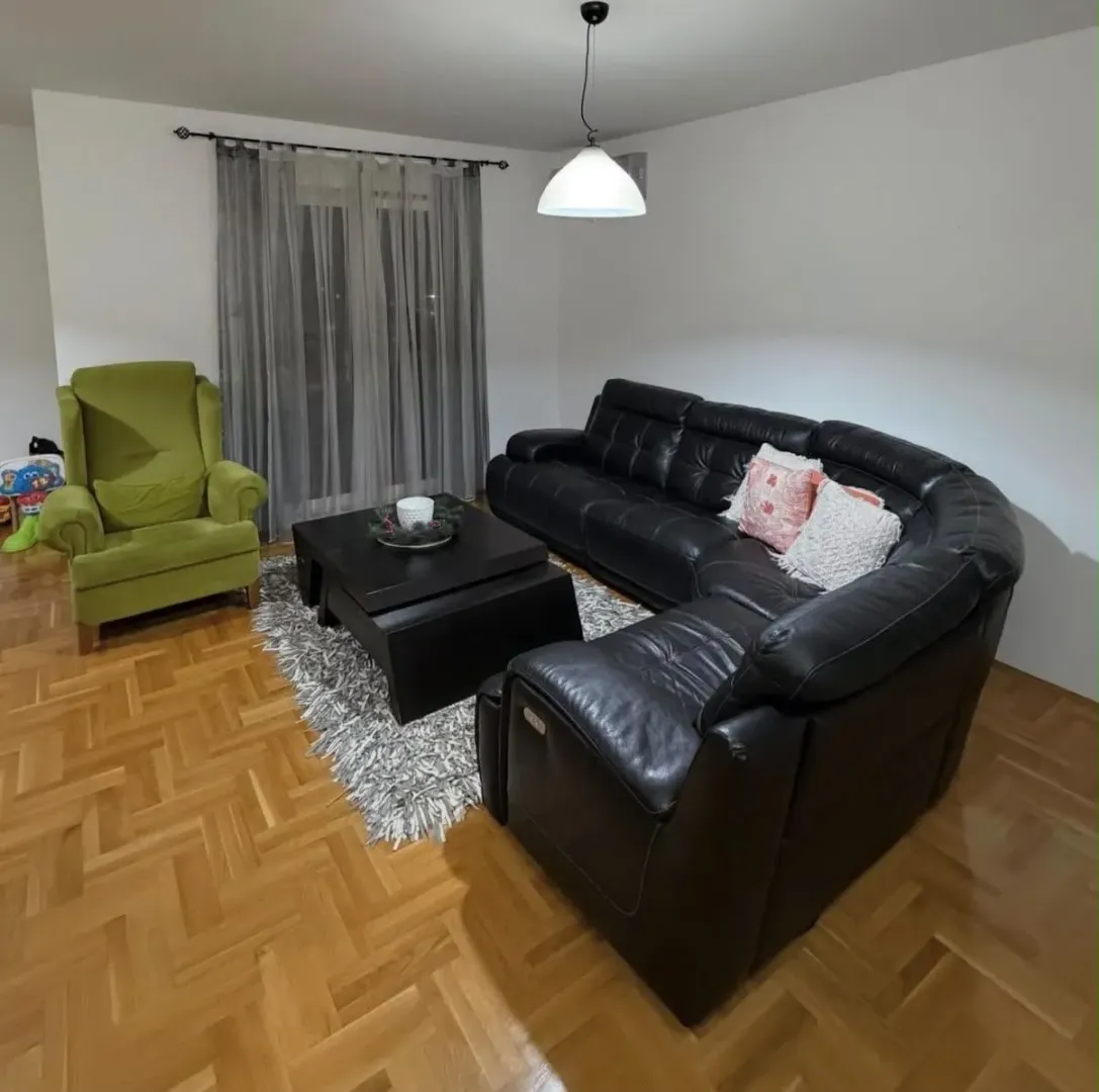 Living room with a sofa set, armchair, and parquet flooring.