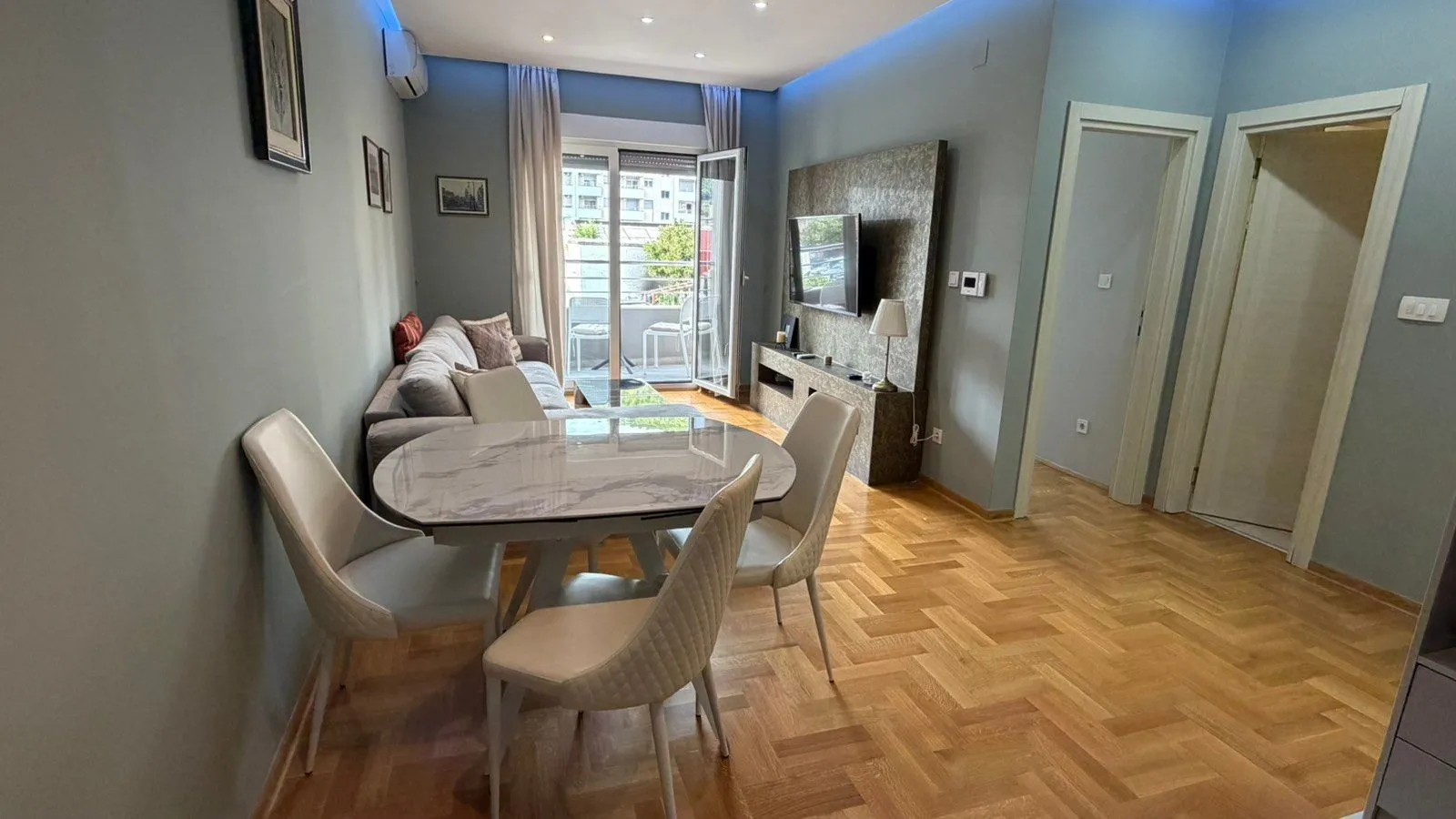 Living room with a dining area, sofa, and balcony access.