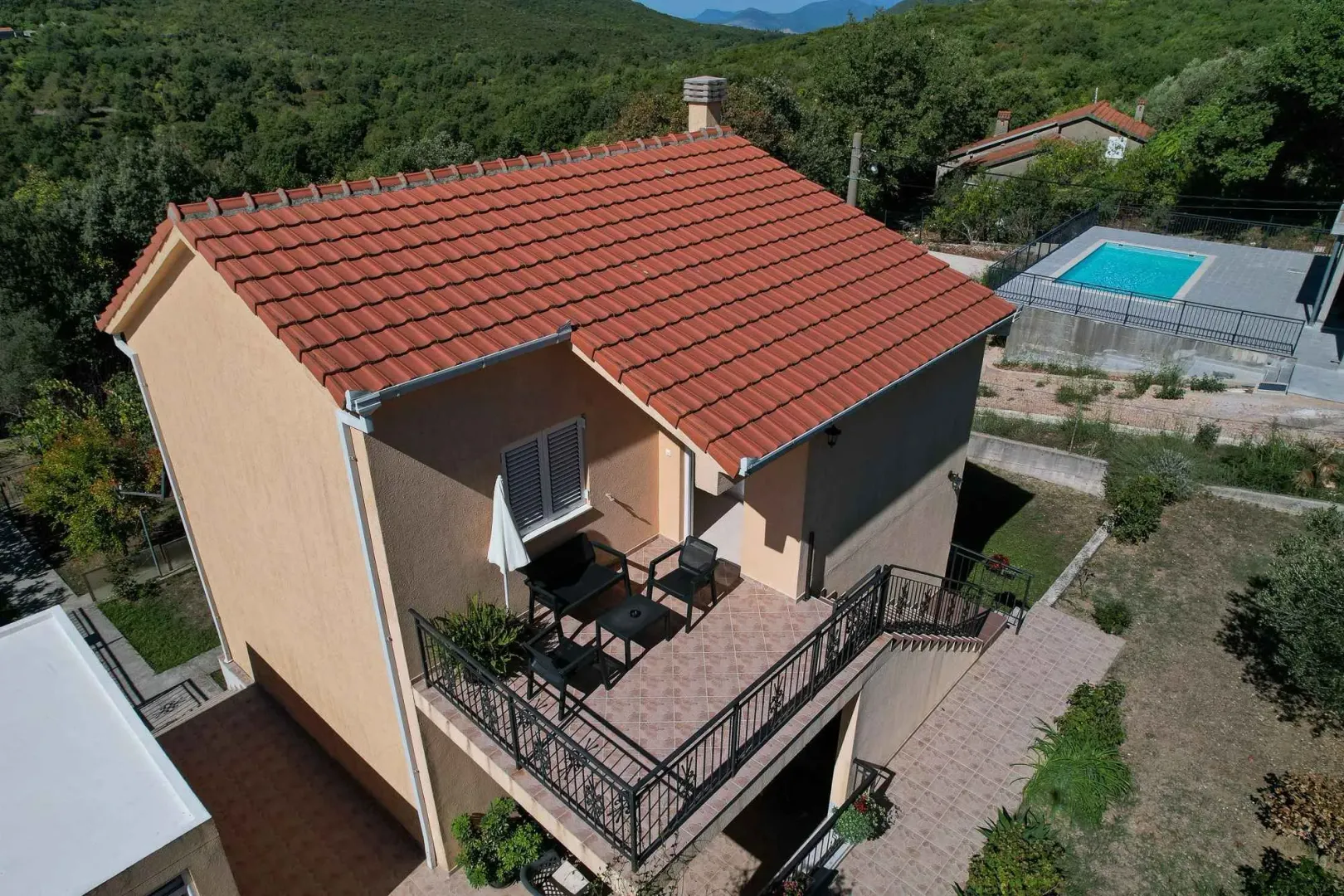 Pogled iz vazduha na spoljašnjost kuće sa terasom i krovom od crijepa.