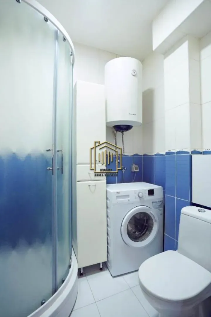 Bathroom equipped with a shower cabin, toilet, washing machine, and water heater.