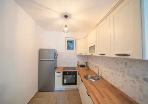 Small modern kitchen with white cabinets and a wooden countertop. - image 15