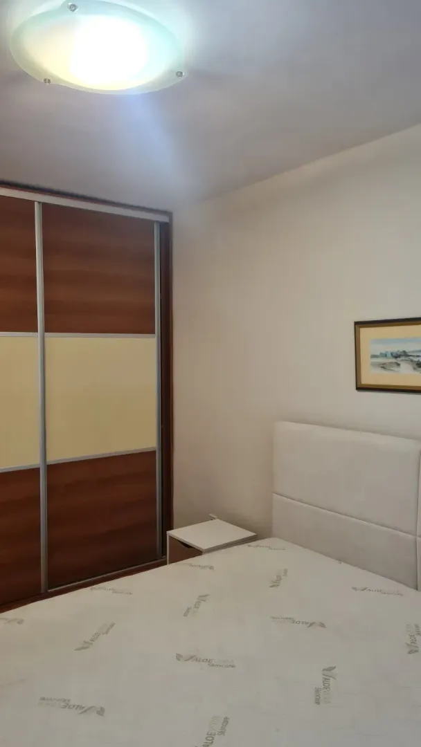 Svijetla spavaća soba sa velikim kliznim plakarom i krevetom.