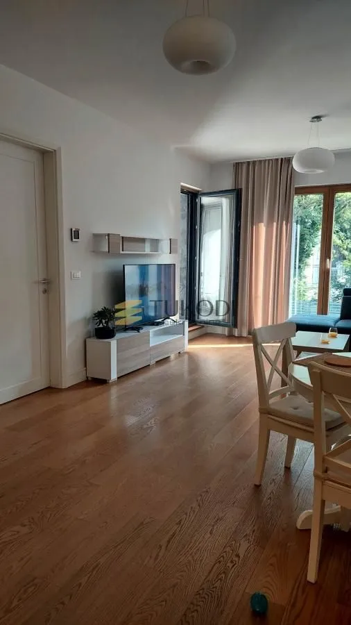Living room with wooden flooring, TV unit, and dining table.