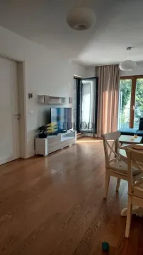 Living room with wooden flooring, TV unit, and dining table. - image 14