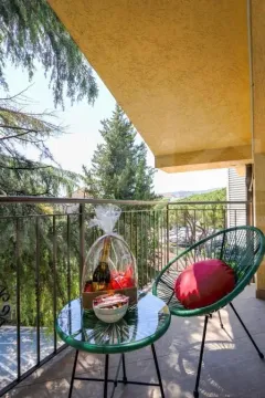 Furnished balcony with a table, chair, and a view of greenery. - image 8
