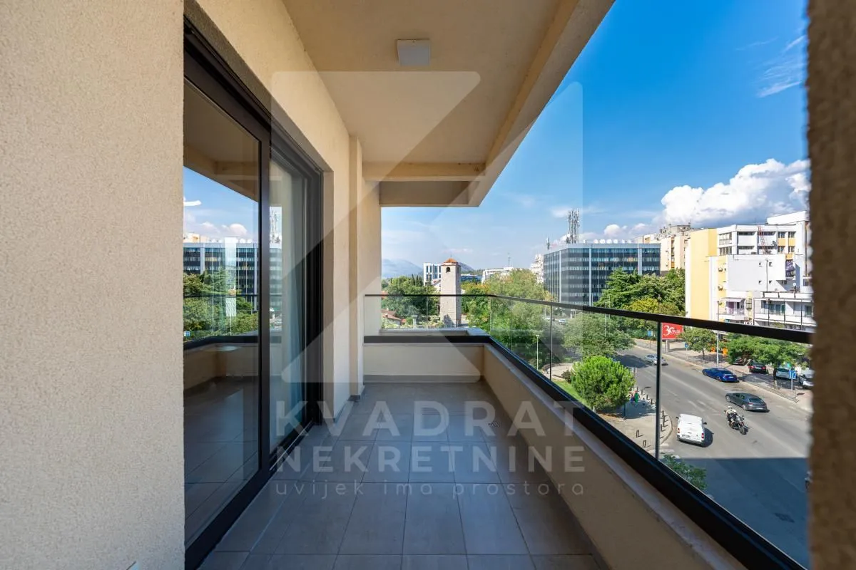 Covered balcony with a glass railing and a view of the city street.