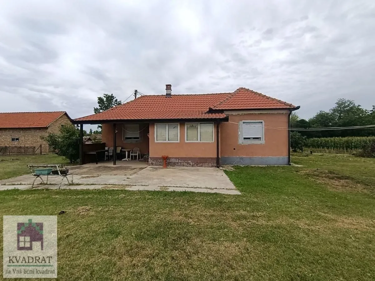 Pogled na zadnju stranu prizemne kuće sa dvorištem.