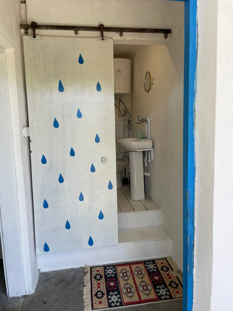 Manje kupatilo sa umivaonikom, wc šoljom i dekorativnim kliznim vratima.