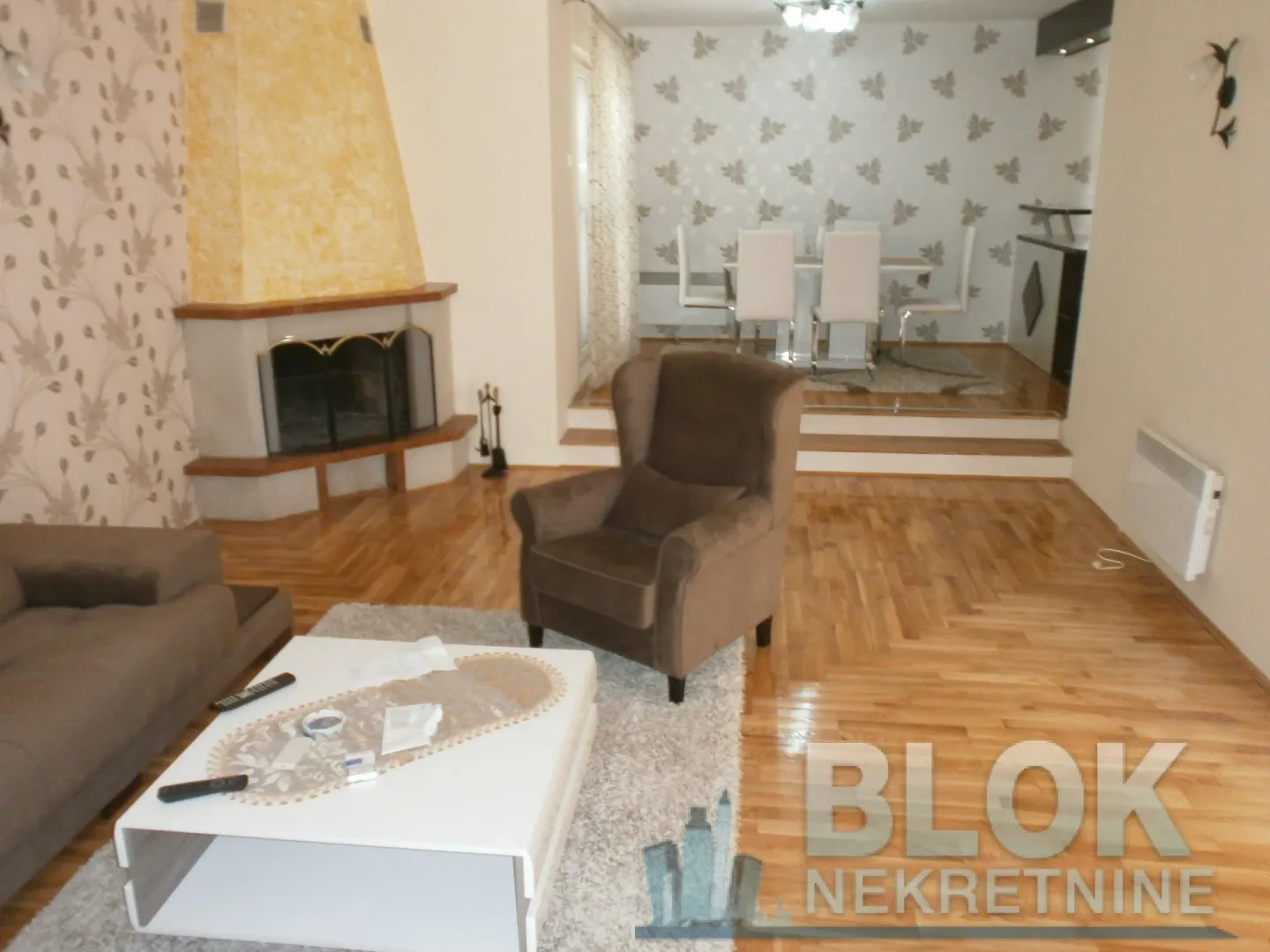 Spacious living room with a sofa, fireplace, and dining area in the background.