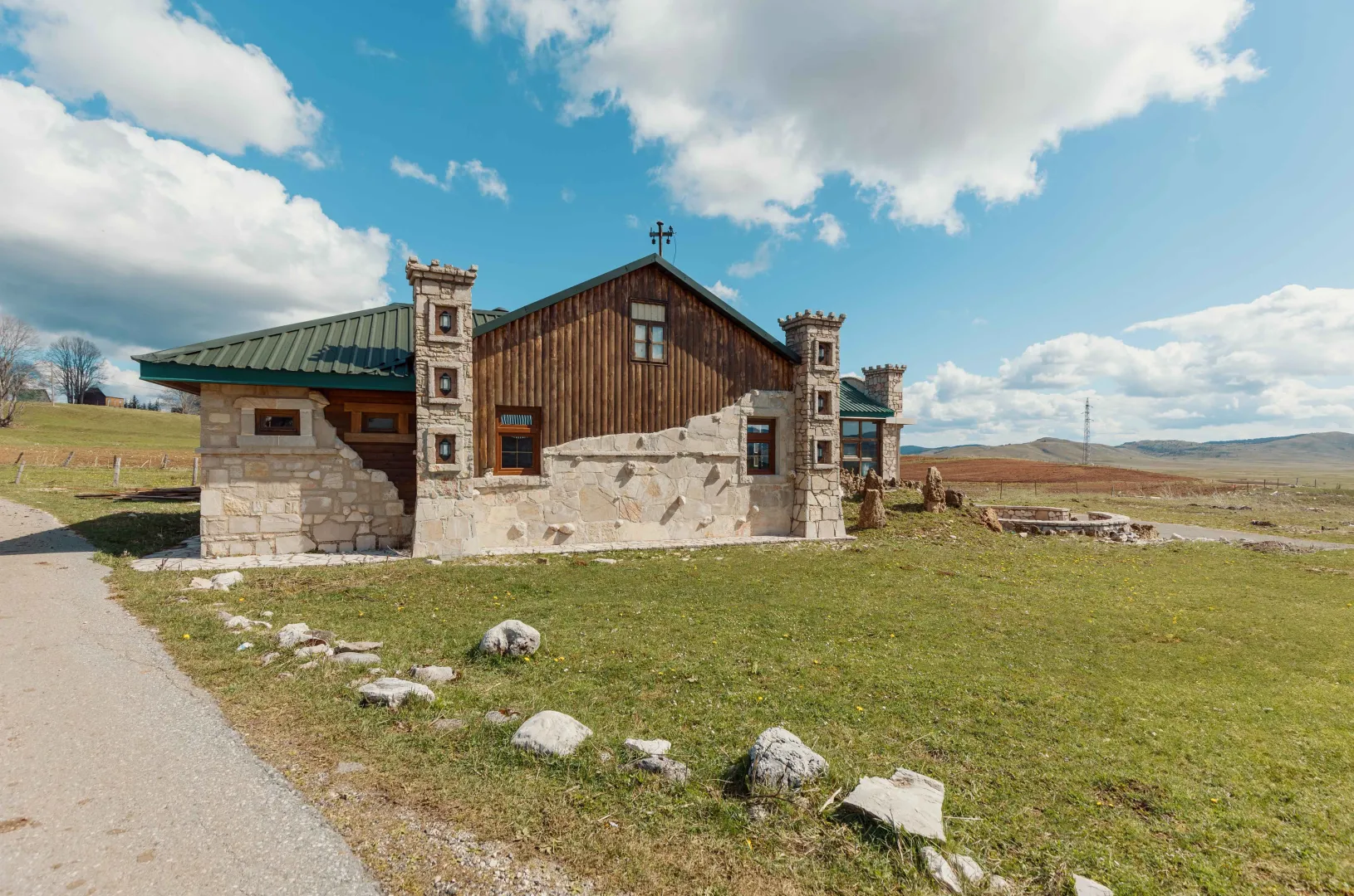 Exterior of a stone house with a wooden facade and yard.