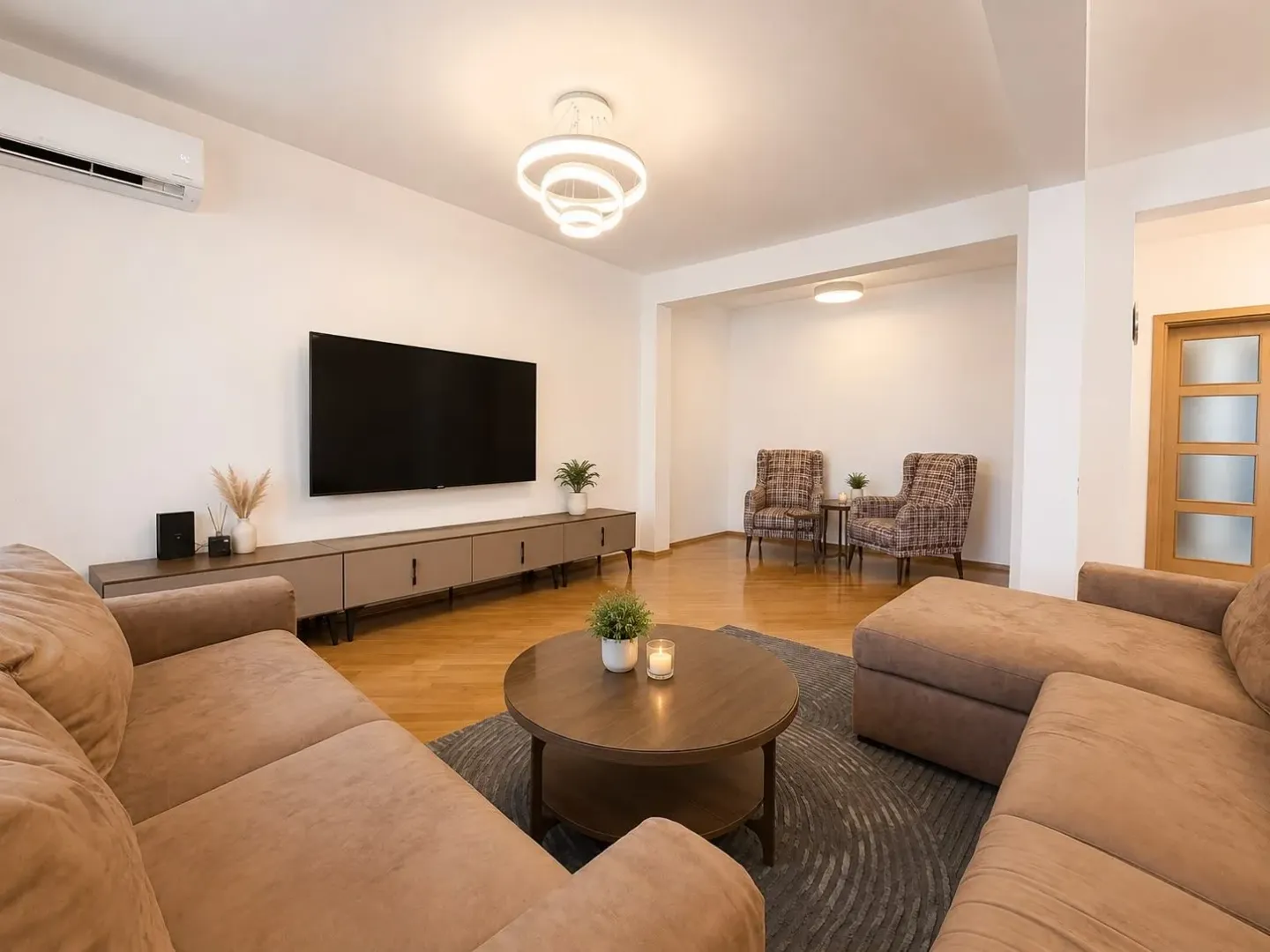 Furnished living room with a sectional sofa, TV, and a seating nook in the background.