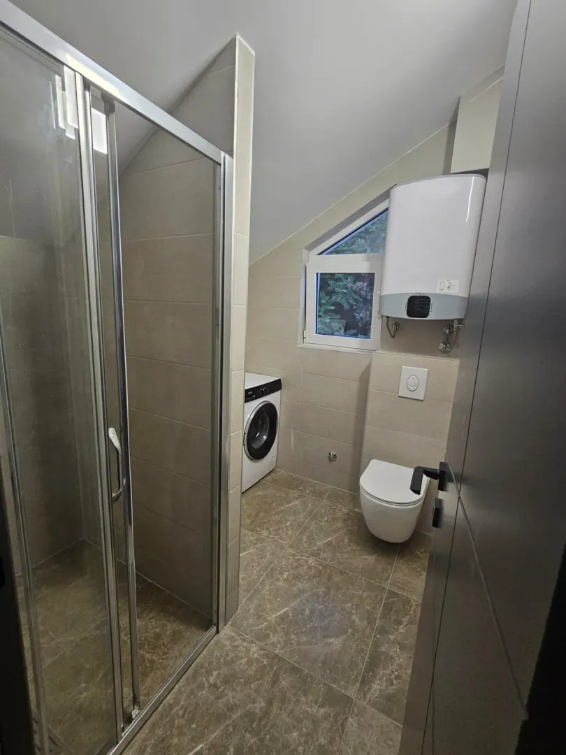 Kupatilo opremljeno tuš kabinom, WC šoljom, mašinom za veš i bojlerom.