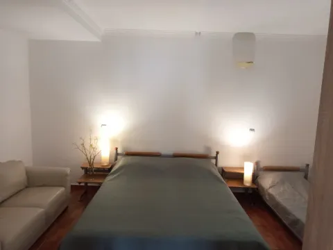 Spacious bedroom with a double bed, extra bed, and a sofa. - image 6